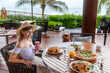 Dine with ocean breeze, young traveler at beachfront restaurant, international cuisine encounter.