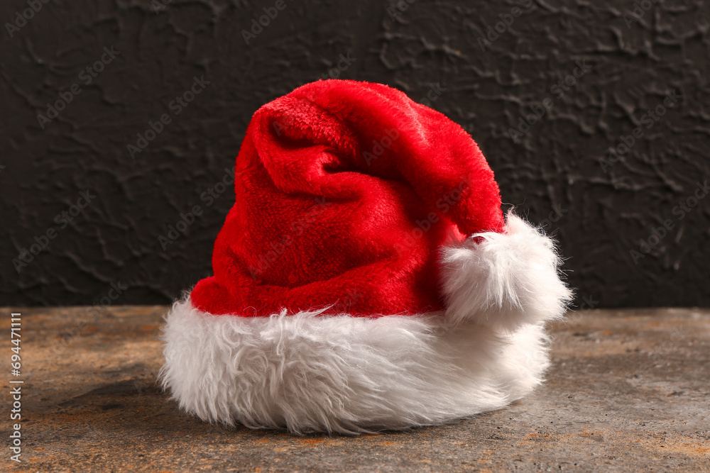 Santa Claus hat on table near black grunge wall