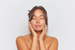 © South House Studio - Portrait of beautiful girl with naked shoulders holding hands on her cheeks with closed eyes, skincare product concept, copy space