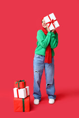 Canvas Print - Beautiful young woman with Christmas gifts on red background