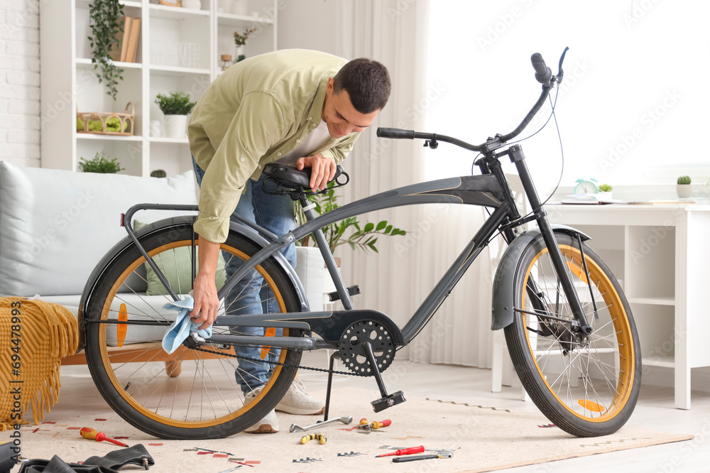 Young man wiping bicycle during repair at home
