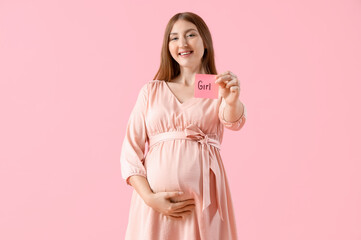 Canvas Print - Young pregnant woman holding paper with word GIRL on pink background