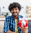 © kucherav - Joyful man presents a gift online, utilizing a webcam to celebrate a special occasion, anniversary, Valentine's Day, or birthday.Virtual connection concept