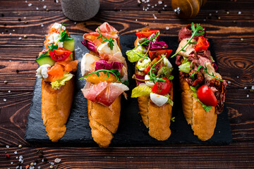 Wall Mural - Starter bruschettas with beef slices, capers, cherry tomatoes, mozzarella, salmon, cucumber, lettuce.