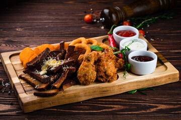 Wall Mural - Breaded squid rings, chicken nuggets, rye bread croutons with cheese, chicken legs and sauces, beer snacks.