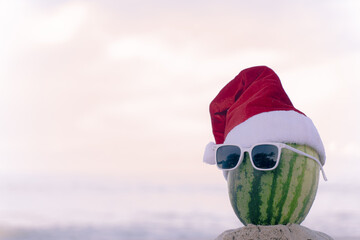 Funny looking watermelon Santa Claus Wear stylish sunglasses on the sand that contrasts with the sea. wearing a christmas hat Christmas and New Year holiday ideas on the beach, Patong Phuket,