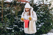 © mdyn - Happy cheerful young Woman with backpack holding red shopping paper bags in hands, walking at street. Winter holidays sale. Shopping banner, holidays and happiness christmas. High quality photo