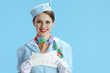 © Alliance - smiling modern female air hostess on blue