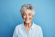 Portrait of happy senior woman smiling at camera on blue background.