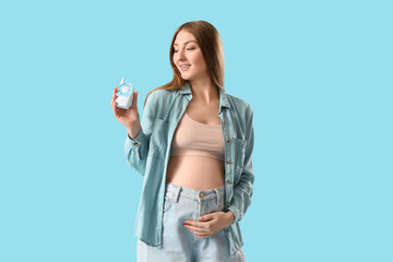 Poster - Young pregnant woman with baby monitor on blue background