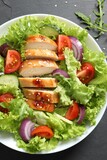 Fototapeta Las - Delicious salad with chicken and vegetables on black table, top view
