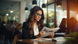 © EmmaStock - Mid-adult businesswoman sitting inside a coffee shop and a reading newspaper