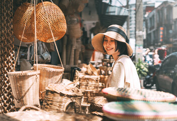 Young adult traveler asian woman travel and shopping at wicker souvenir shop at local street Chiang Mai, Thailand