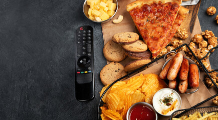 Wall Mural - Unhealthy food i basket. TV remote control and snacks - chips, popcorn, cookies, cheese, sauce, fries, pizza