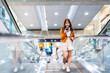 Young asian woman in international airport terminal or modern train station. Backpacker passenger female commuter walking on escalator