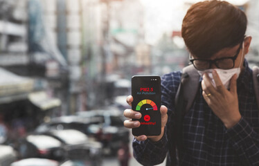 Asian man using a smartphone scanning the weather over smog city from PM2.5 dust. View of buildings with bad weather from Fine Particulate Matter.City air pollution and Unhealthy concept.pm2.5