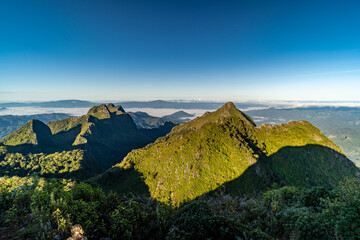 Wall Mural - View from the top of Doi Luang Chiang Dao during a morning sunrise with trees and shrubs in the foreground and beautiful mountain ranges in background