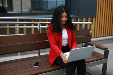 Wall Mural - beautiful african woman in red jacket working with laptop