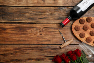 Poster - Red wine, chocolate truffles, corkscrew and roses on wooden table, flat lay. Space for text