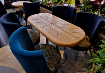 Wall Mural - oval-shaped restaurant table with geometric grooves in the surface. lots of flowers around. suede upholstered dining table chairs. flowered covers