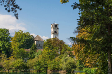 Wall Mural - The Captain's Tower and Saint Anthony of Padua Church in central Bihac, Una-Sana Canton, Federation of Bosnia and Herzegovina. The River Una is in the foreground