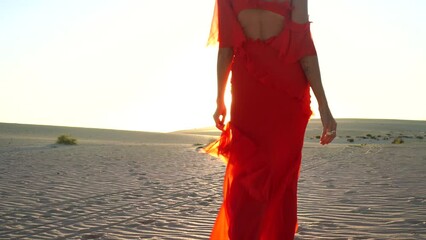 Wall Mural - Elegant woman in red fashionable dress walking on the desert during sunset. Fuerteventura island.
