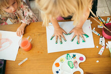 Girl Making Handprint With Watercolors On Paper At Home
