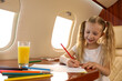 © New Africa - Cute little girl drawing at table in airplane during flight