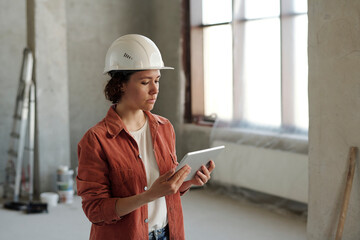Engineer wearing hardhat and using tablet PC at construction site