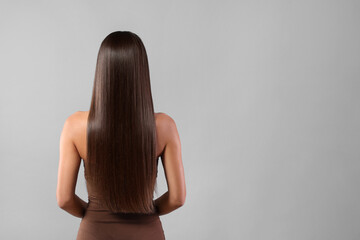 Wall Mural - Hair styling. Woman with straight long hair on grey background, back view and space for text