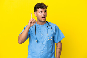 Sticker - Young surgeon doctor man isolated on yellow background intending to realizes the solution while lifting a finger up