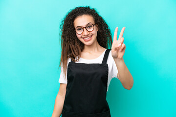 Wall Mural - Restaurant waiter Arab woman isolated on blue background smiling and showing victory sign