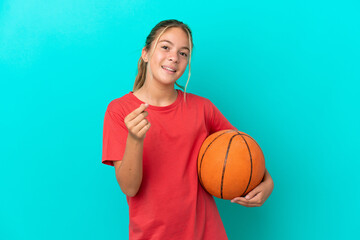 Wall Mural - Little caucasian girl playing basketball isolated on blue background making money gesture