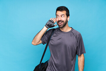 Wall Mural - Young sport man with beard over isolated blue background listening to something by putting hand on the ear