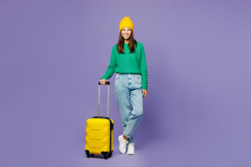 Wall Mural - Full body traveler fun happy woman wearing casual clothes hold suitcase bag isolated on plain purple background. Tourist travel abroad in free spare time rest getaway. Air flight trip journey concept.