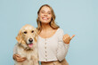 Young owner woman with her best friend retriever dog wear casual clothes point finger aside on area mockup copy space isolated on plain pastel light blue background studio Take care about pet concept