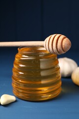 Wall Mural - Jar with honey, garlic and dipper on blue wooden table, closeup