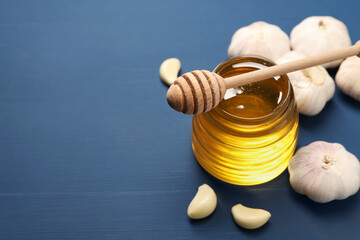 Wall Mural - Jar with honey, garlic and dipper on blue wooden table, closeup. Space for text