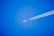 an airplane and the traces it leaves on a blue sky.