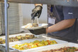 © triocean - Buffet style service - Canteen worker at serving line putting food on the plate