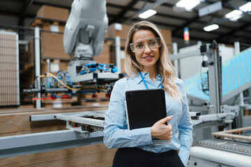Wall Mural - Female manager standing in modern industrial factory. Manufacturing facility with robotics and automation. Female leader, CEO in heavy industry, manufactury.