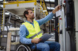 © Halfpoint - Portrait of man in wheelchair working in modern industrial factory, in adjustable workstation. Concept of workers with disabilities, accessible workplace for employees with mobility impairment.