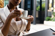 © ADDICTIVE STOCK - Unrecognizable black businesswoman drinking coffee while sitting at table