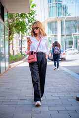Poster - Full length of an attractive mid aged woman walking on the city street and using smartphone