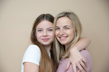 Wall Mural - beautiful young, teenager girl together with her beautiful mother posing in front of brown background