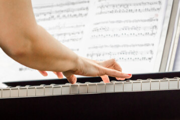 female hands of a pianist musician and piano keys close up