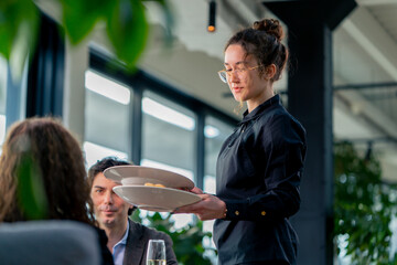 Wall Mural - a girl waiter serves orders to guests the concept of hospitality and service in a high-class restaurant