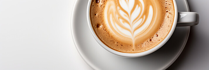 Wide panoramic top view photo of a Cappuccino coffee cup with cream design on it and a saucer in white background