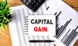 CAPITAL GAIN text on a notebook with chart and calculator
