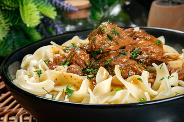 Wall Mural - Pasta with beef stew in black bowl.